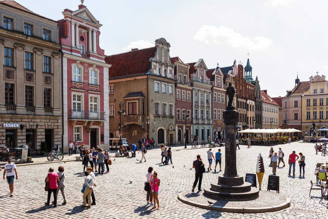 Poznan's historic Old Town square with colorful Renaissance buildings and crowds of people.