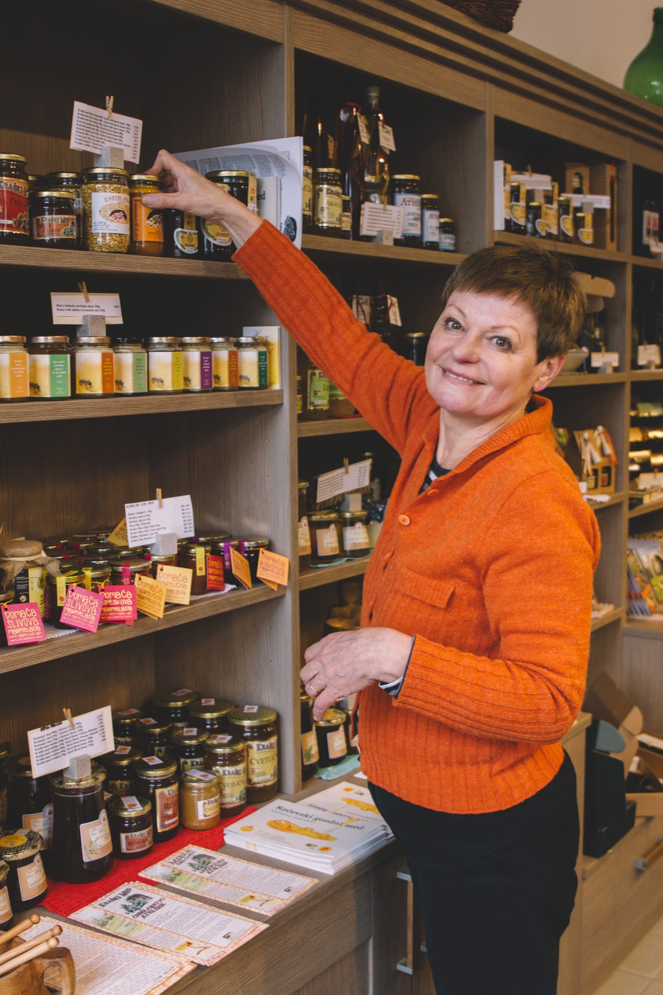 Slava Sosic points to a jar on wooden shelves stocked with Slovenian food products at Krasevka delicatessen.