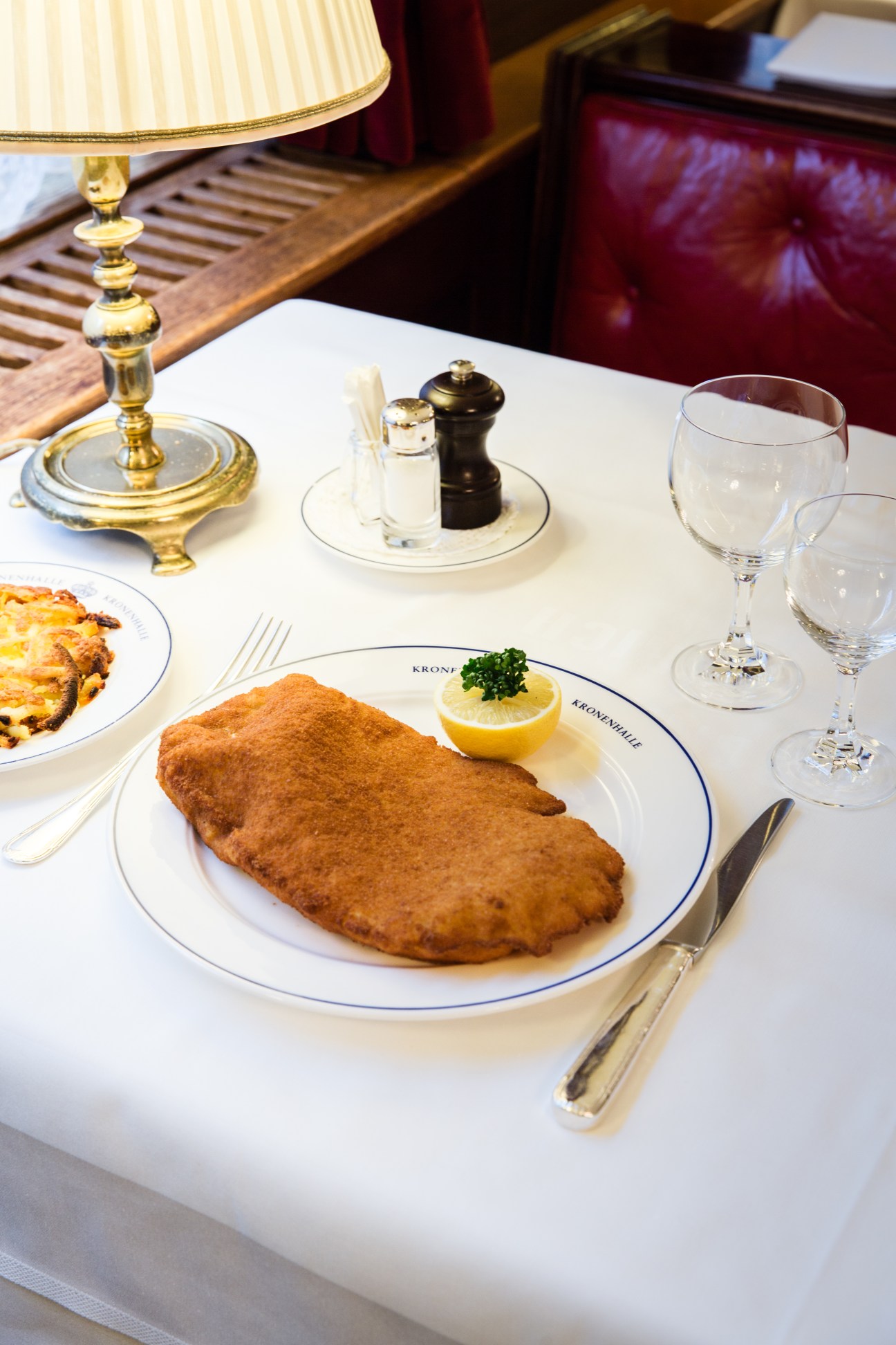 Wiener schnitzel served on a white plate with blue rim, garnished with lemon and parsley at Kronenhalle restaurant.