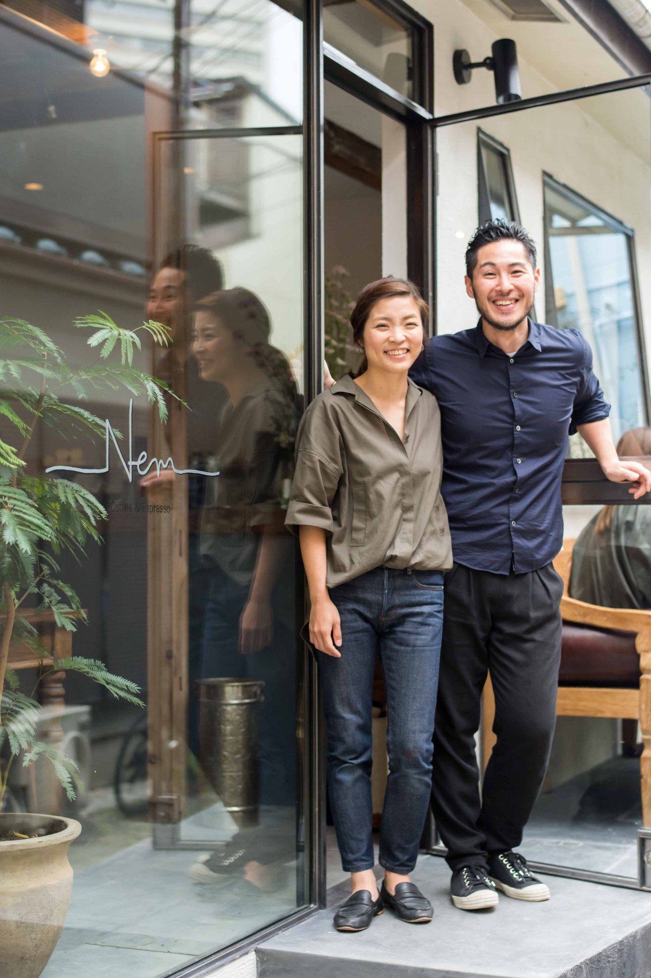 Akiyo and Takumi Watanabe stand smiling outside Nem Coffee & Espresso in Tokyo's Hiroo neighbourhood.