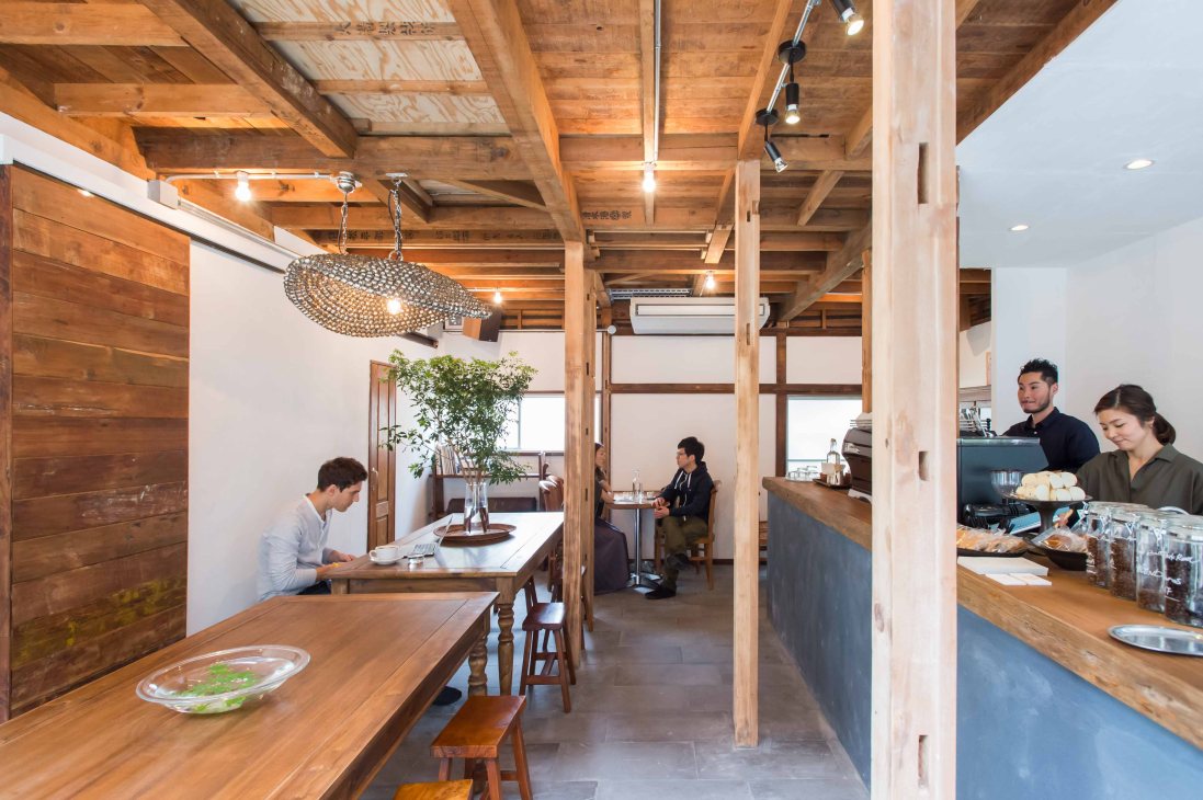 Interior of Nem Coffee & Espresso in Tokyo showing wooden beams, counter seating, and staff.