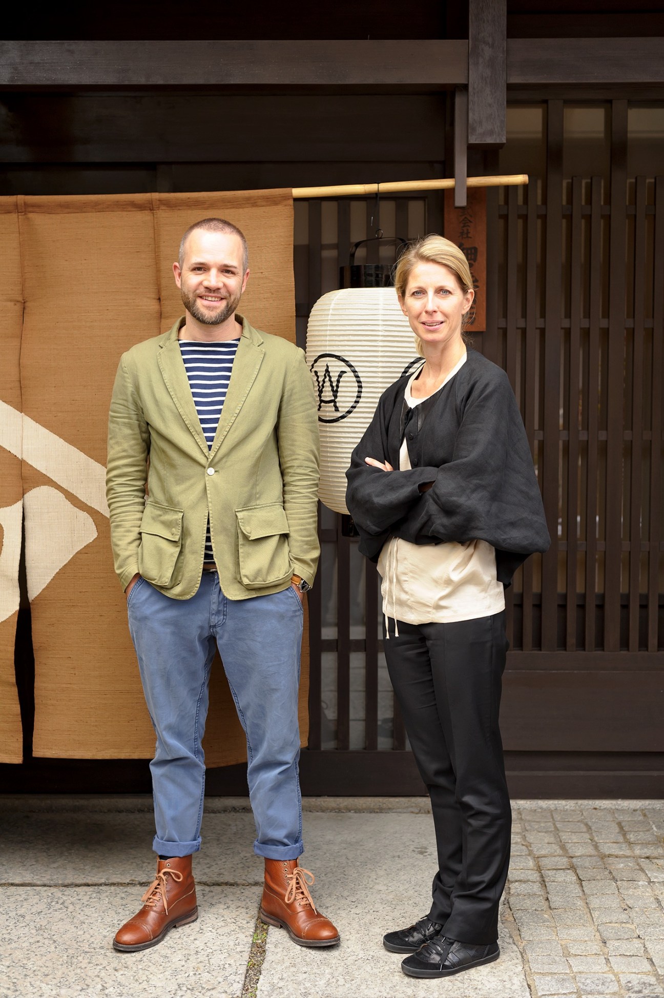Thomas Lykke and Anne-Marie Buemann stand in front of traditional Japanese wooden doors and Hosoo textile display.