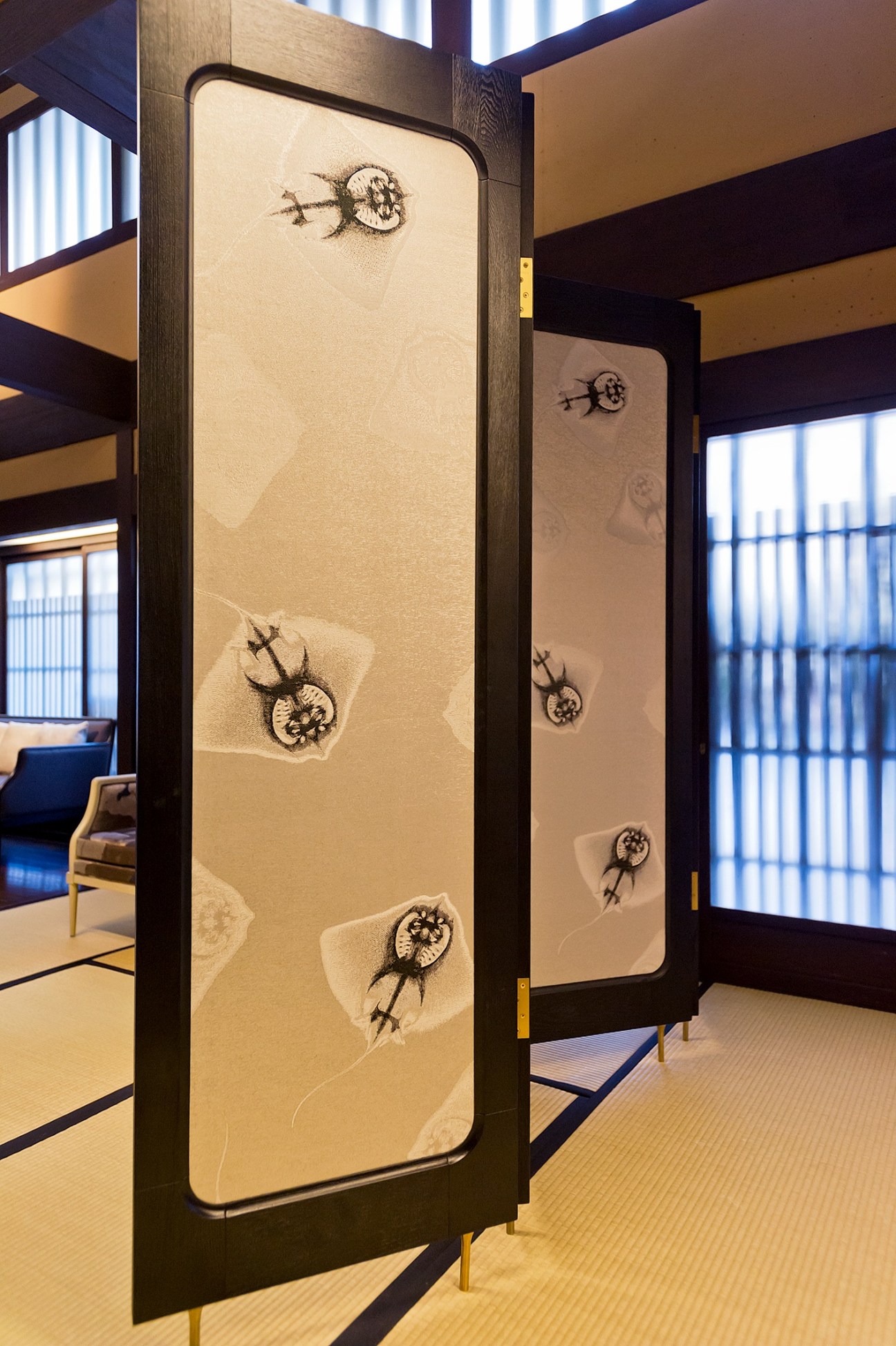 Stellar Works screen with Hosoo chrysanthemum textile pattern in cream and black, displayed in modern interior space.