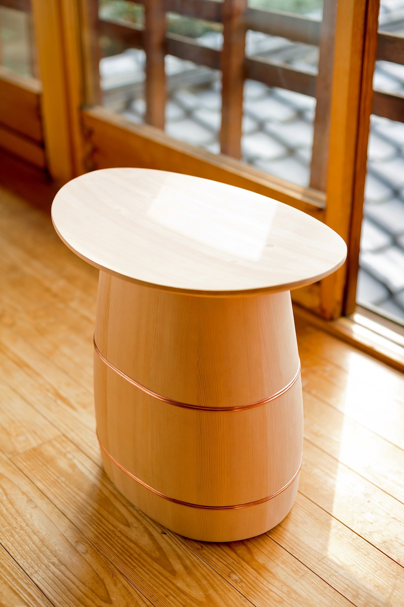 Turned wooden stool by Shuji Nakagawa with cream-colored top and natural wood base on wooden floor.