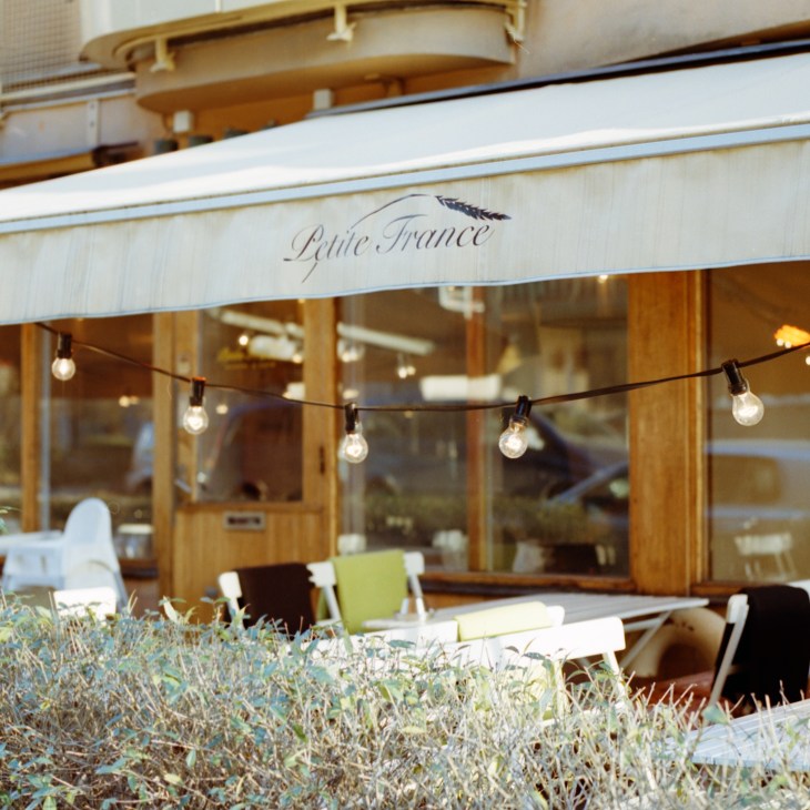 Storefront of Petite France bakery with wooden facade and awning displaying the name.