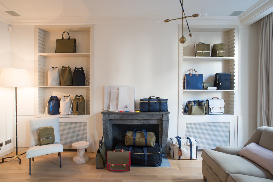 L/Uniform showroom displaying bags and backpacks on shelves and fireplace mantel.