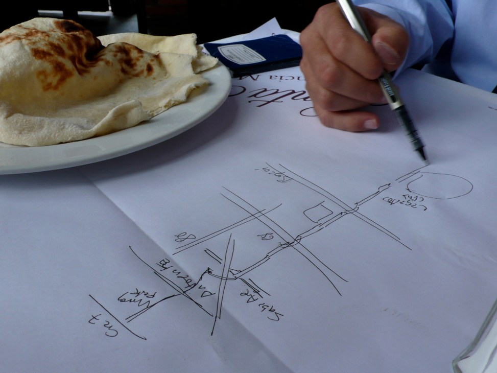 Enrique Peñalosa sketches a map of Bogotá's bike routes on a paper table setting while dining.