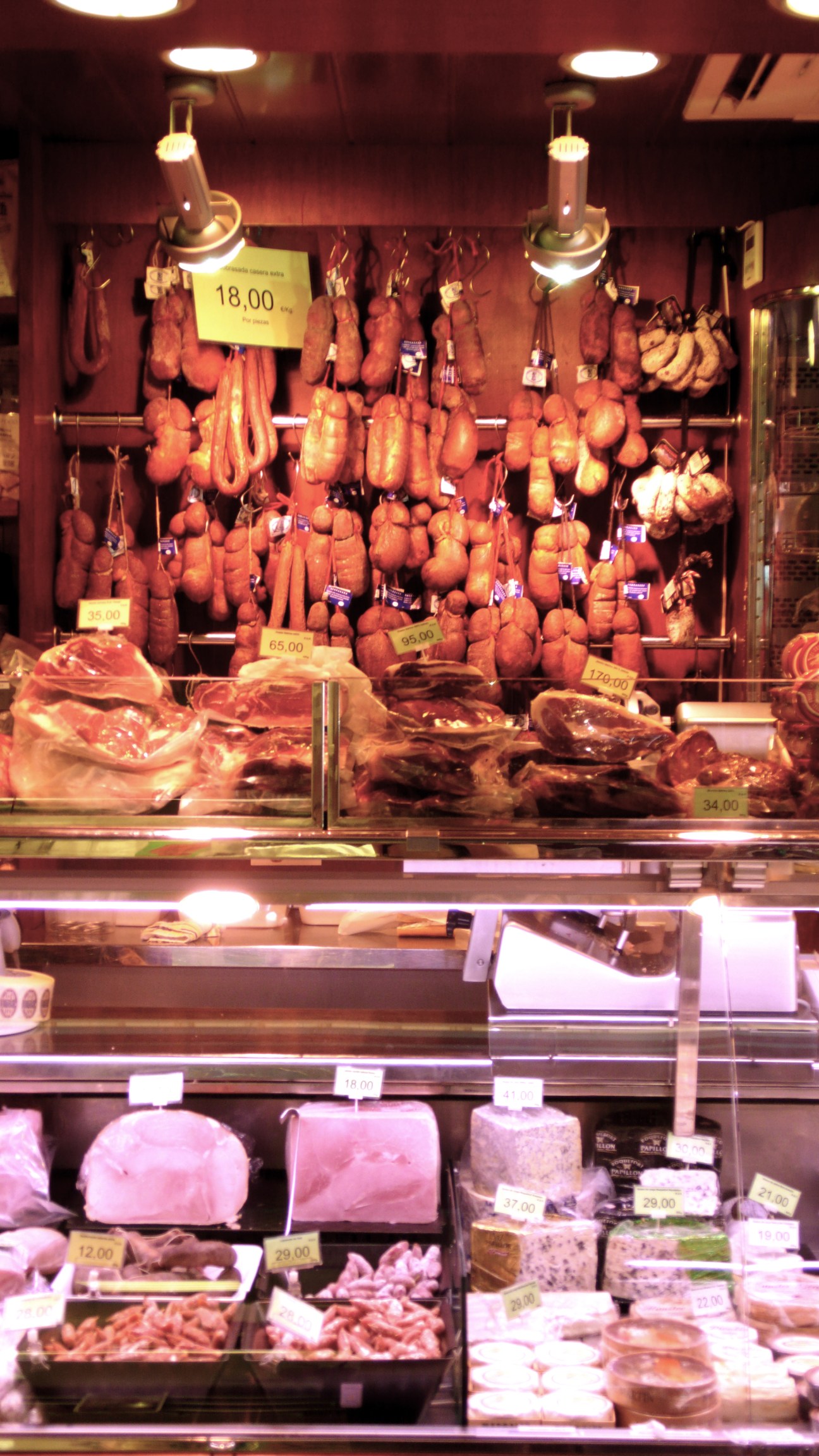 Butcher shop display window with hanging cured meats and fresh cuts behind glass counter