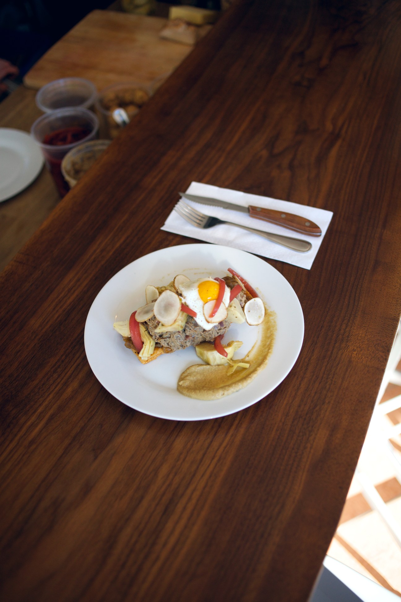 Plated dish at La Famille restaurant with meat, egg, and vegetable garnishes on white plate.