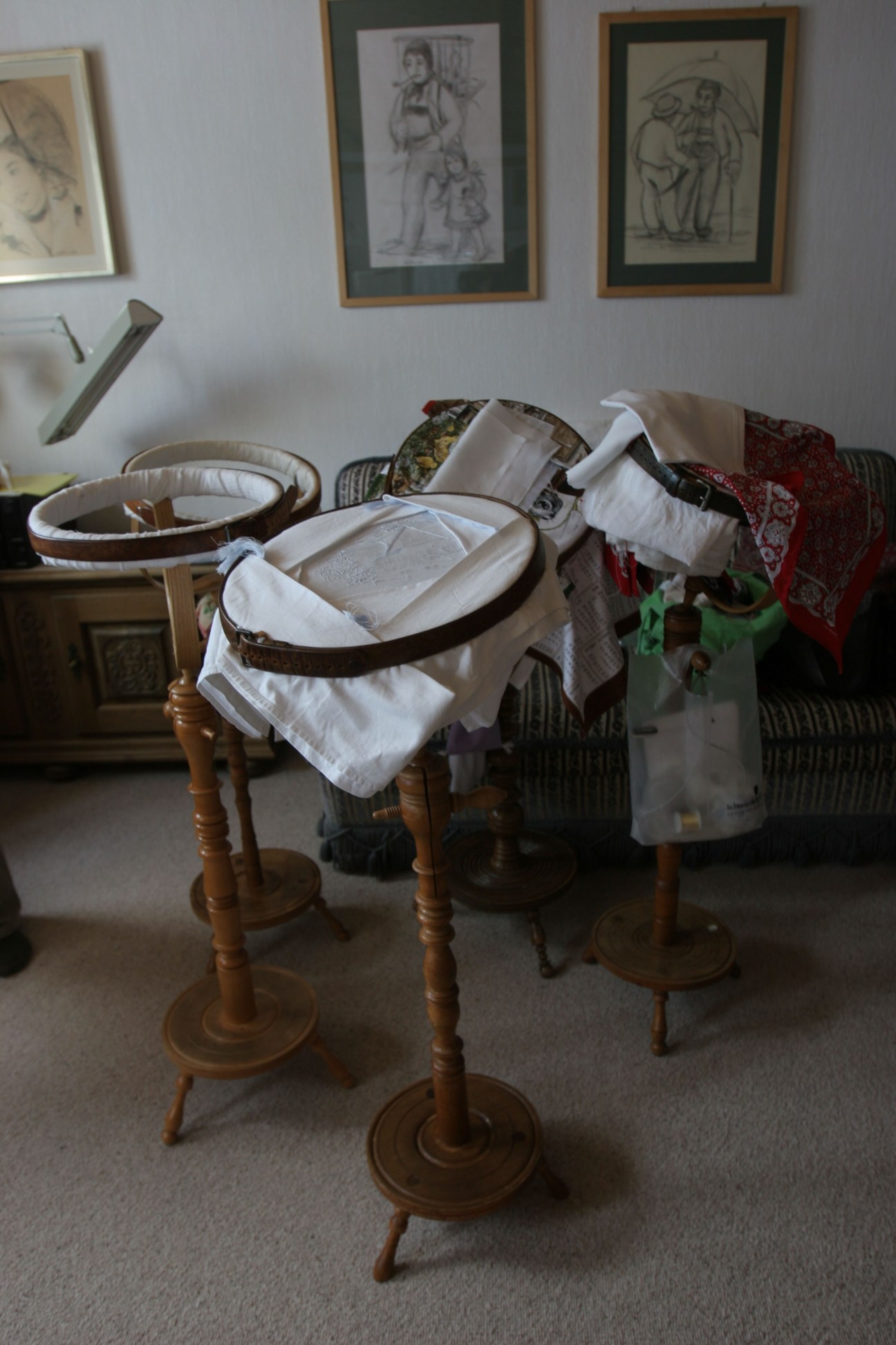 Embroidered linens and textiles draped over wooden stands ready for needlework at Ebneter & Biel.