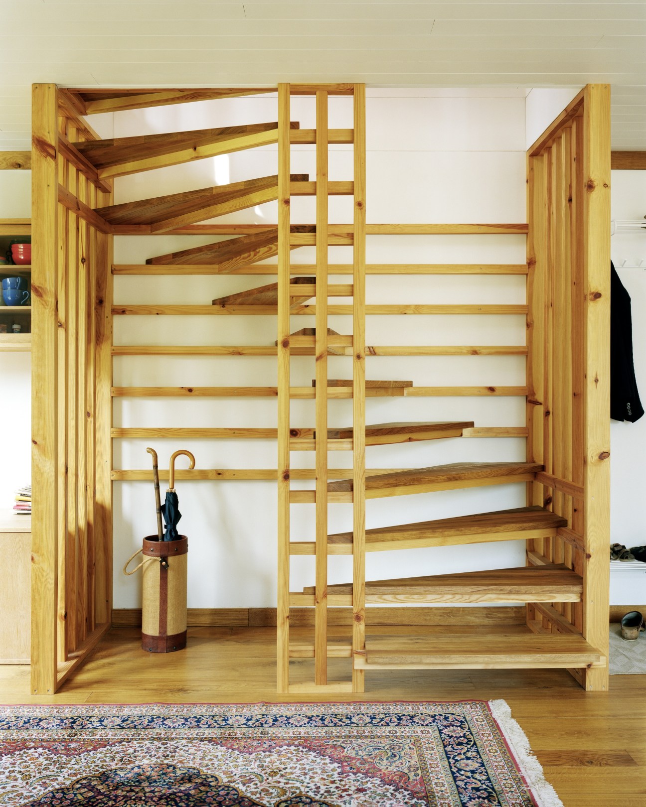 Pine and oak staircase with geometric lattice pattern and darker wood treads in a bright interior space.