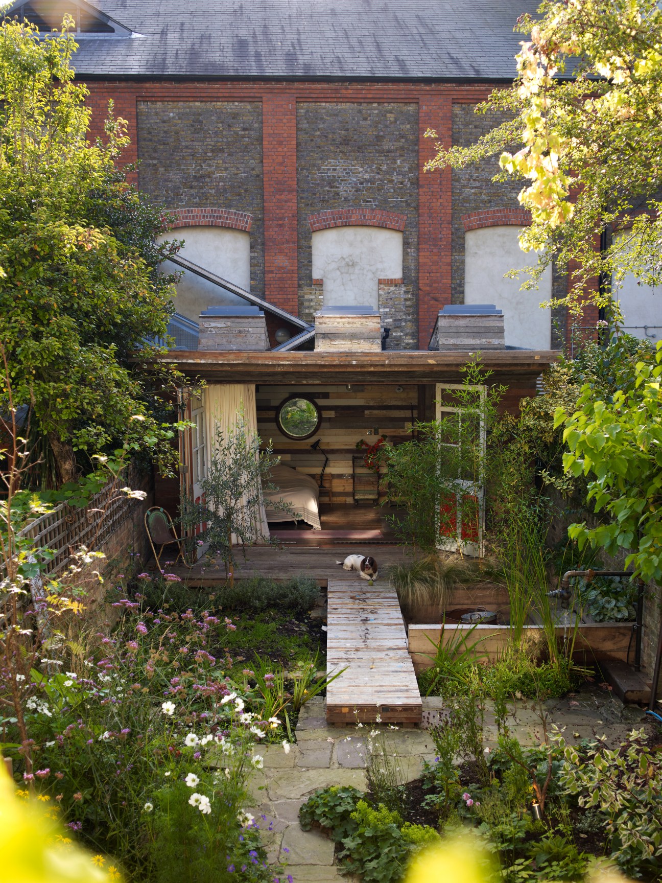Garden cabin in Hampstead, London featuring ivy-covered walls, wooden deck and salvaged materials by Retrouvius.
