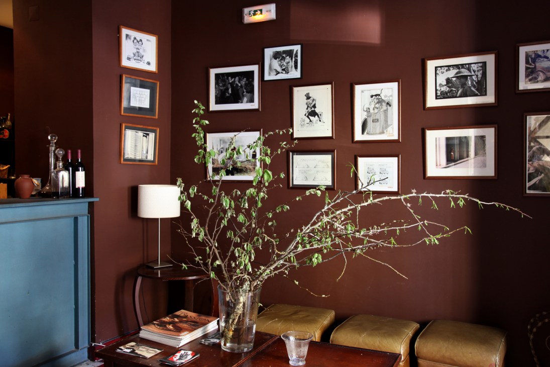 Interior of Clube de Jornalistas with burgundy walls, framed photographs, and botanical arrangement.