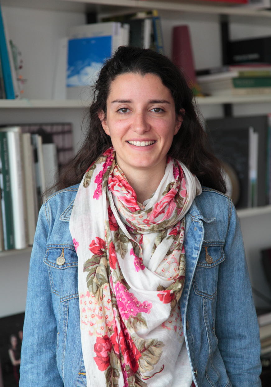 Carlota Cabral, a student resident of Lapa, smiles at the camera wearing a denim jacket and floral scarf.