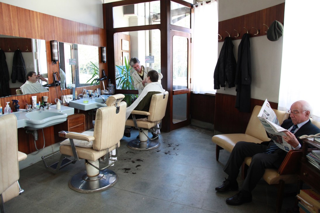 Interior of Melcar barber shop with vintage chairs, wooden paneling, and customers