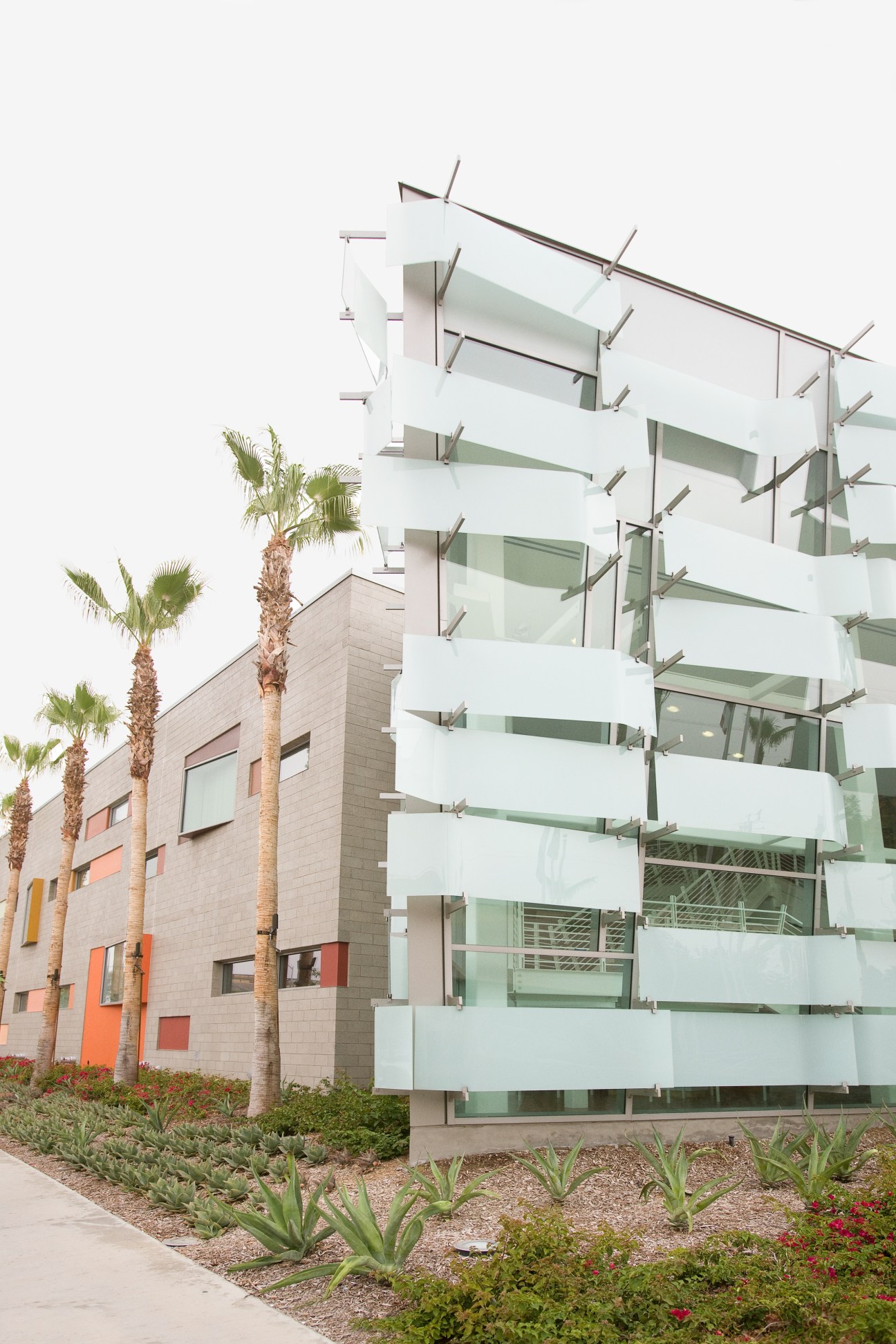 Modern glass and stone police station with angular white balconies and colorful accent panels.