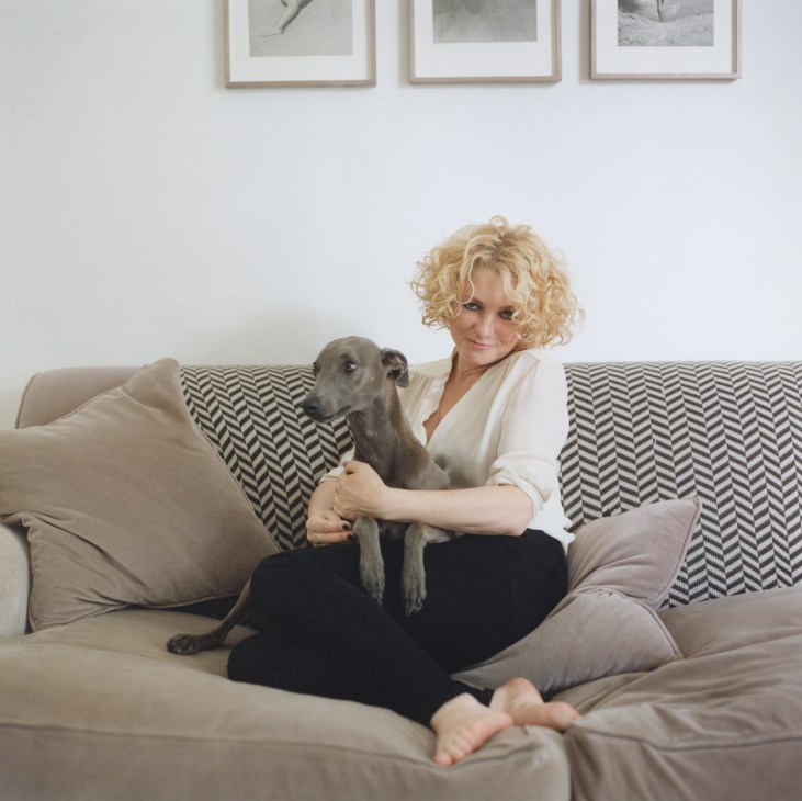 Alison Goldfrapp sits on a beige sofa with her pet whippet, Maus, in her east London home.