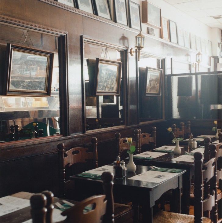 Interior of Toff's fish restaurant with wooden chairs, framed landscape pictures on walls, and table settings.