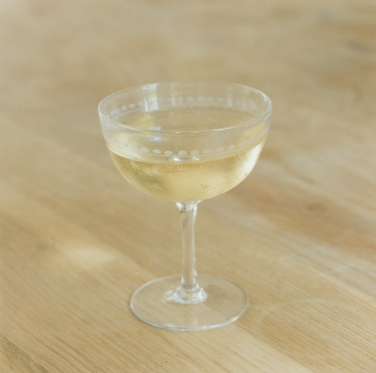 Glass of pale English sparkling wine on a wooden surface.