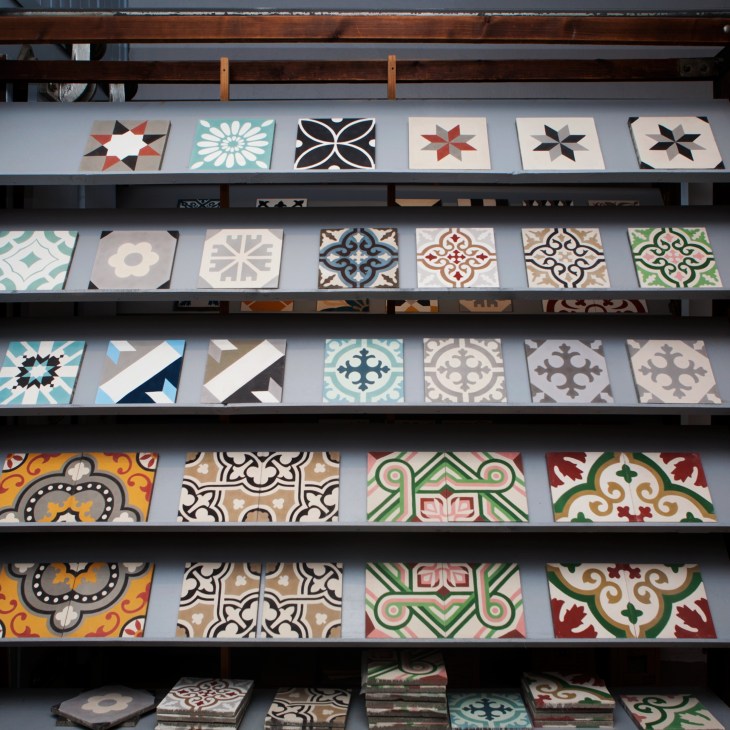 Shelves displaying decorative cement tiles with various geometric and floral patterns in multiple colors.