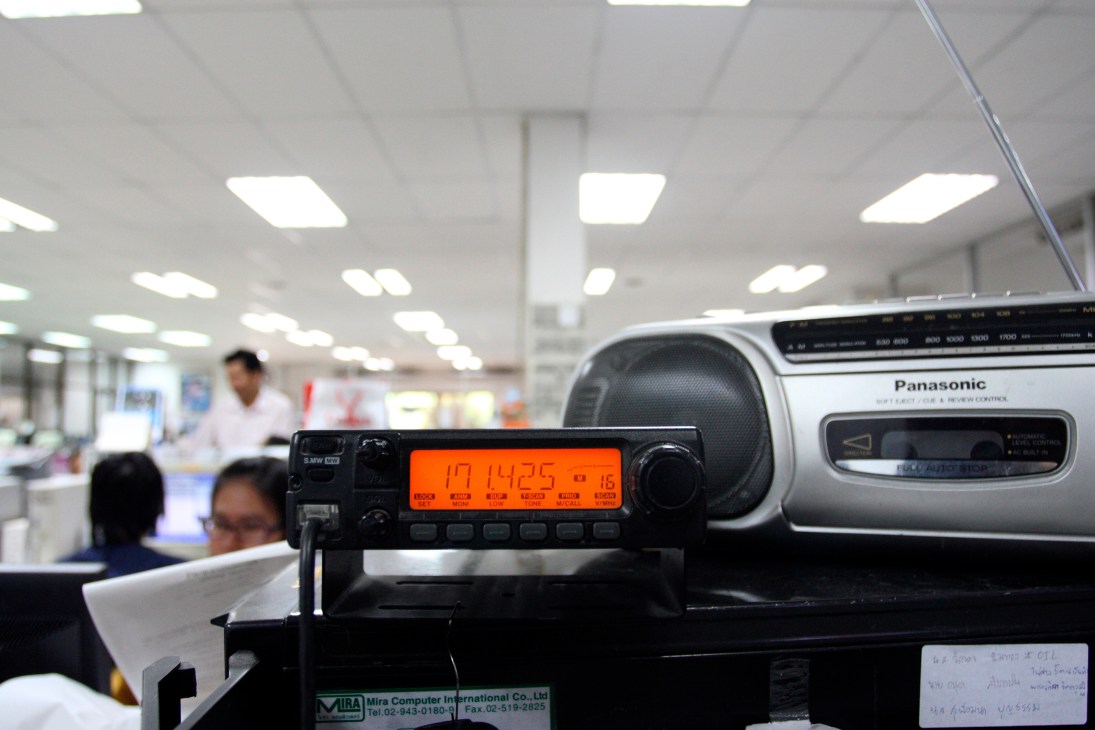 Radio equipment with orange display screen in RDCK radio studio with staff visible in background