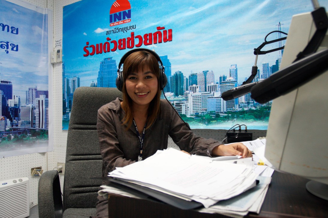 Yaowalak Taosen, 25, reads the news at RDCK radio station in Bangkok wearing headphones.