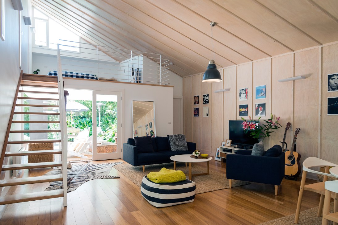 Light-filled modern home studio with wooden ceiling, black sofa, and mezzanine loft space in Braddon, Canberra.