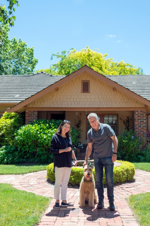 Bente and Lee Phillips stand with their Airedale terrier outside their brick home in Braddon, Canberra.