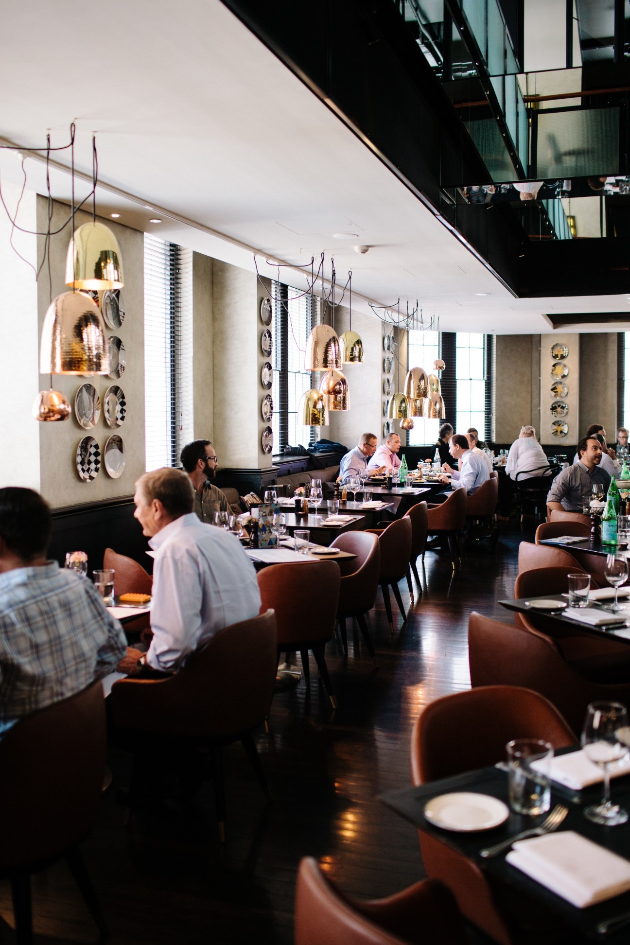 Interior of QT restaurant showing diners at tables during busy lunchtime service with modern pendant lighting.