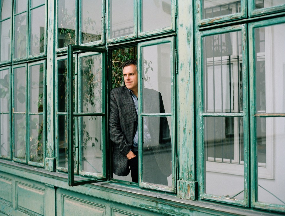 Christoph Thun-Hohenstein stands at an open window with distressed green-painted frames.