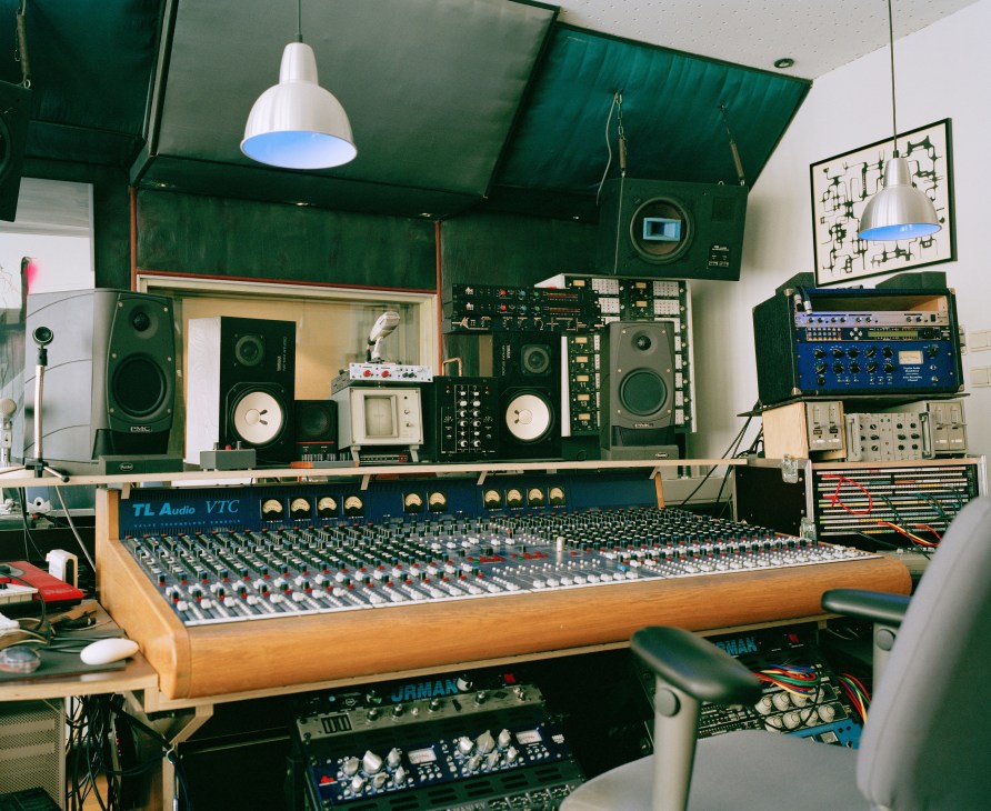 Patrick Pulsinger's recording studio with mixing console, synthesizers, speakers, and green-walled production space.