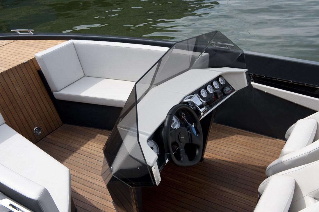 Interior view of a Frauscher motor boat showing steering wheel, dashboard controls, white seating, and wooden deck.