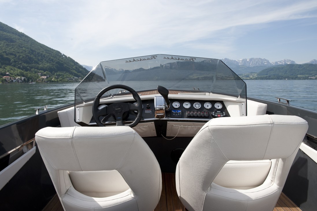 Interior of a Frauscher Lido 686 motorboat with white seats and dashboard on an Alpine lake.