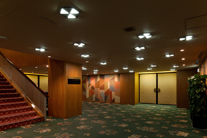 Hotel Okura's banqueting room with wooden walls, pendant ceiling lights, and patterned carpet.
