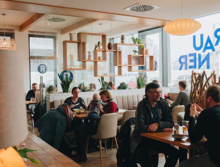 Diners enjoy meals at modern restaurant Rauner in Linz with contemporary wooden shelving and large windows