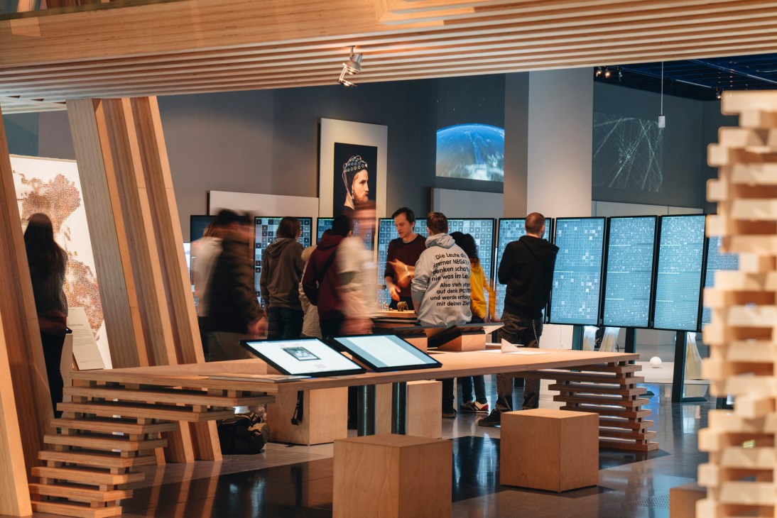 Visitors explore interactive digital displays and exhibits in a modern museum with wooden architecture