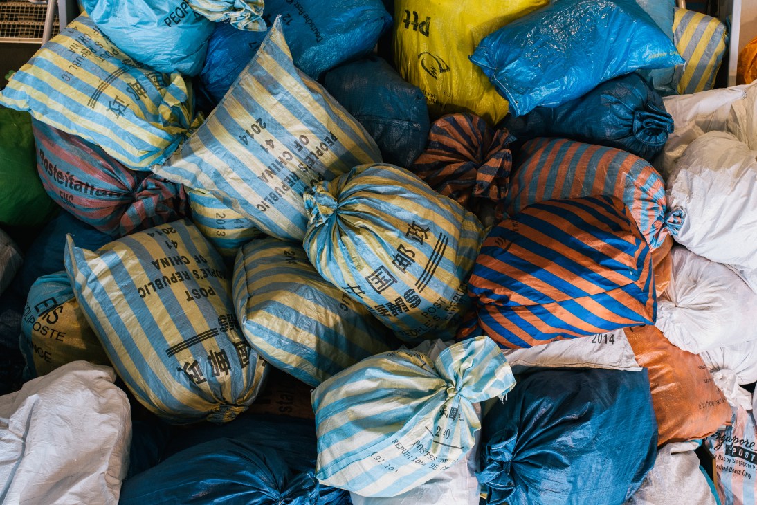 Colorful striped mail sacks in blue, yellow, and orange stacked at Hongkong Post's Air Mail Centre.