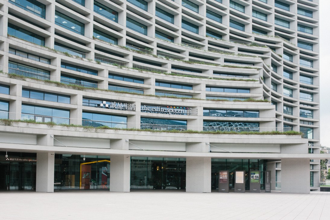 Eslite Spectrum exterior showing modernist curved building facade with balconies and ground-floor retail storefronts.