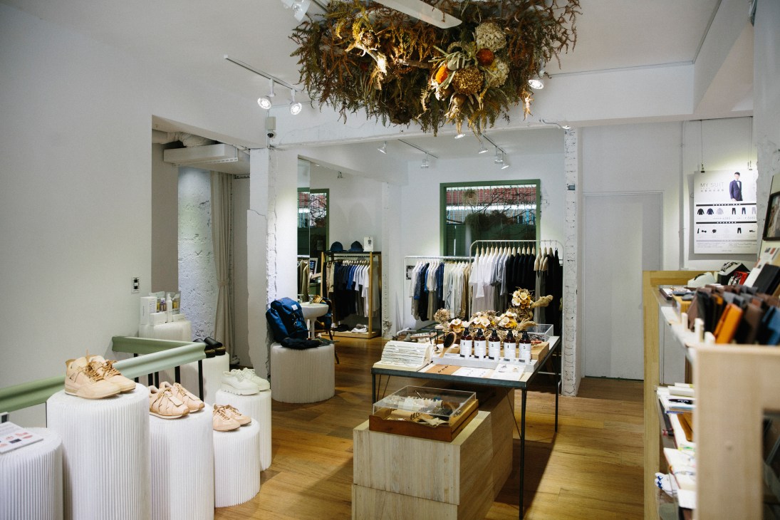 Interior of Fujin by Plain-me menswear shop with clothing racks, display pedestals and dried flower installation.
