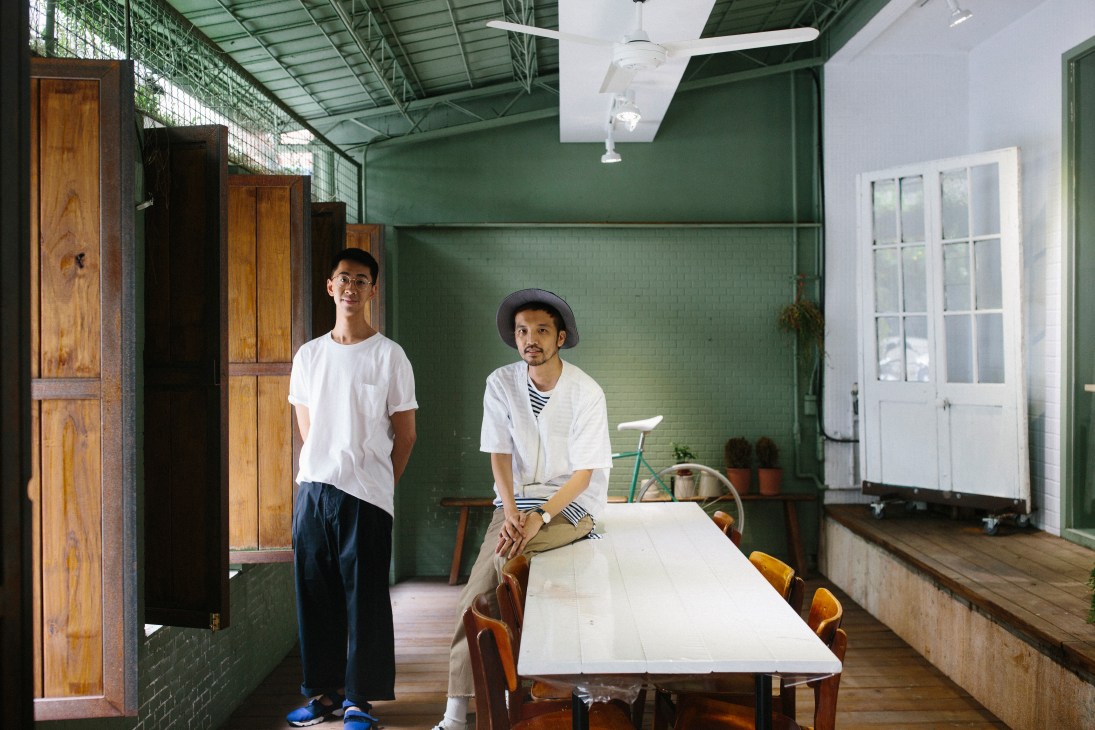 Plain-me co-founder Akko Liu and staff member in green-walled retail space with wooden furniture.