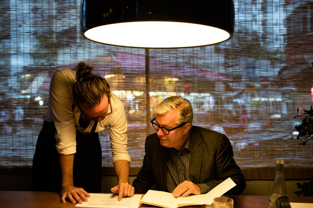 Restaurant owner Charles Pelletier and museum director Lars Nittve discuss menu options at a dining table.