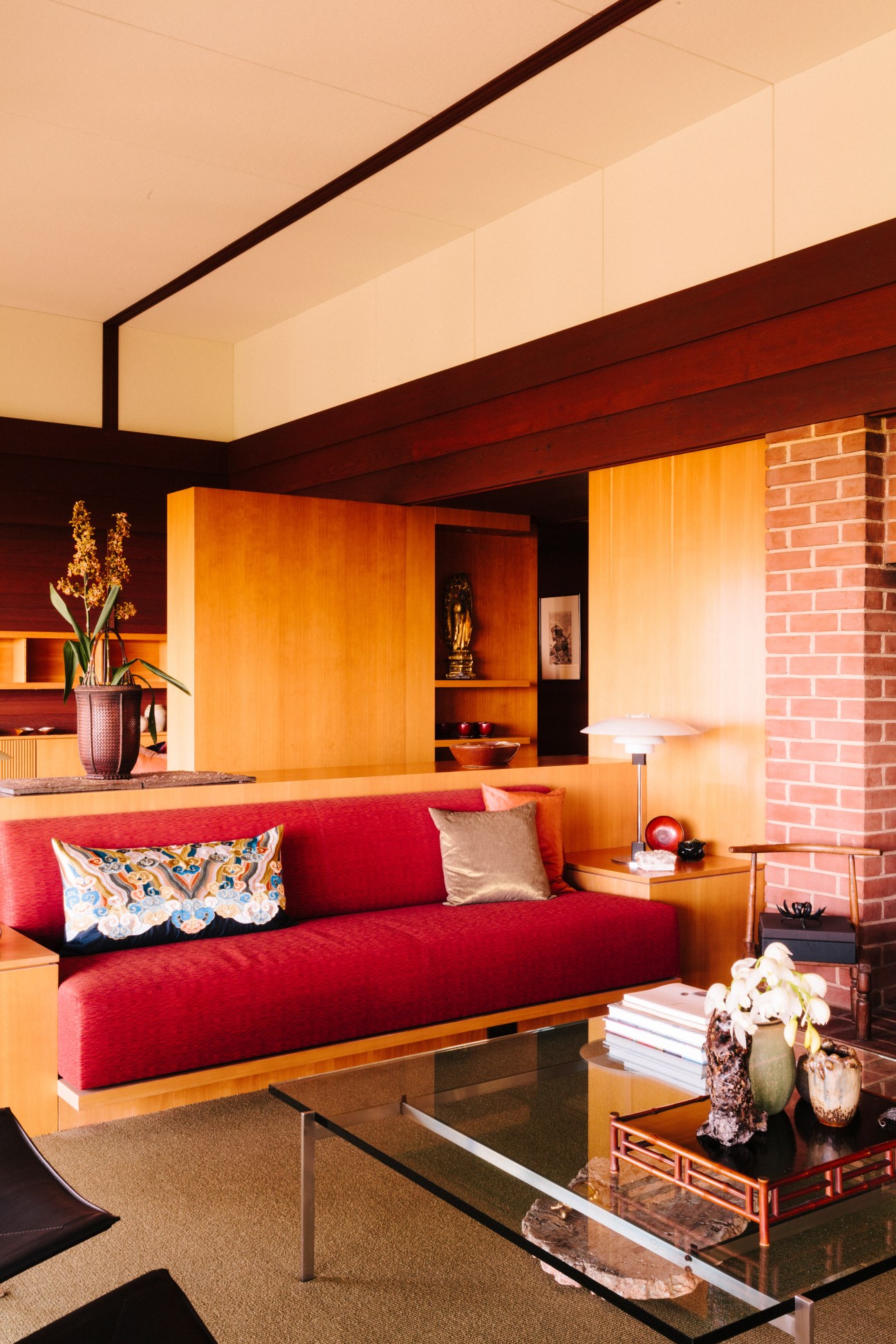 Modernist living room with red built-in sofa, orange wood paneling, and Poul Henningsen table lamps.