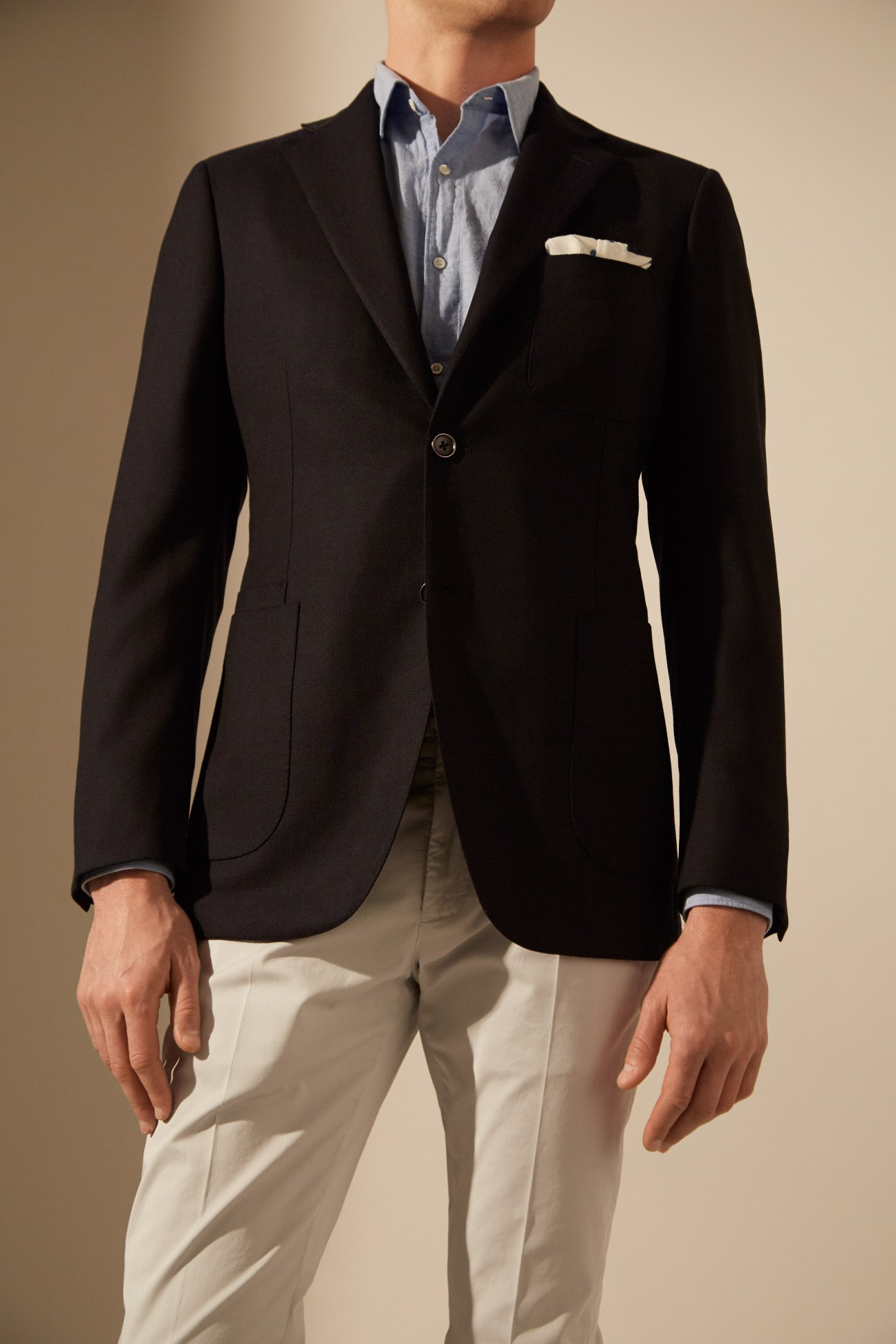 Man wearing a black Belvest jacket, Aspesi shirt, Incotex trousers, and Drake's pocket square.
