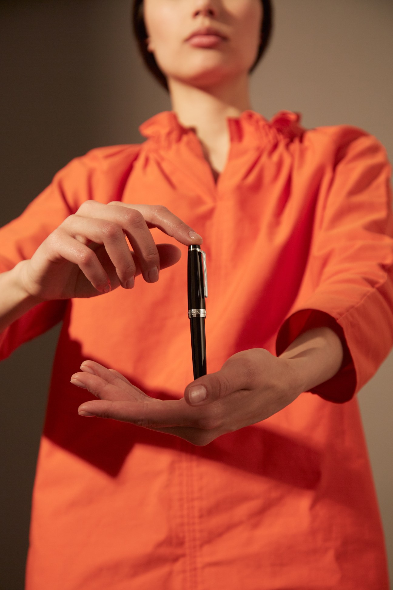 Person in orange dress holding a black Sailor pen