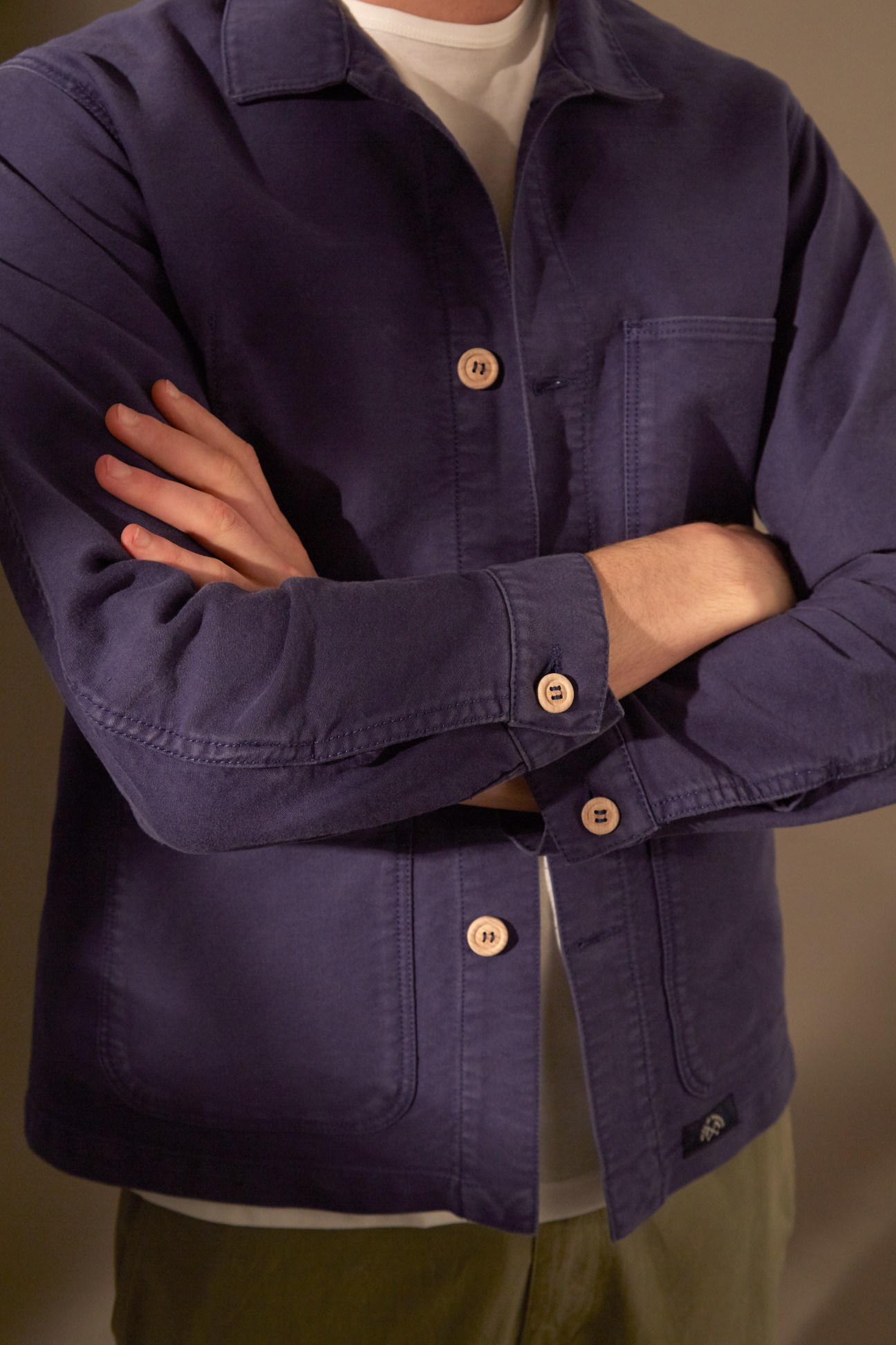 Person wearing a navy Bleu de Paname jacket with wooden buttons over a cream t-shirt and olive trousers.