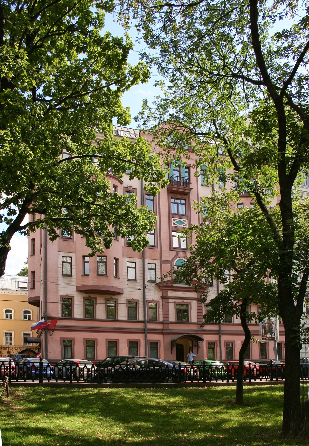 Pink early 20th-century building on Tverskoi Boulevard in Moscow housing The New Times magazine headquarters, partially obscured by green trees.