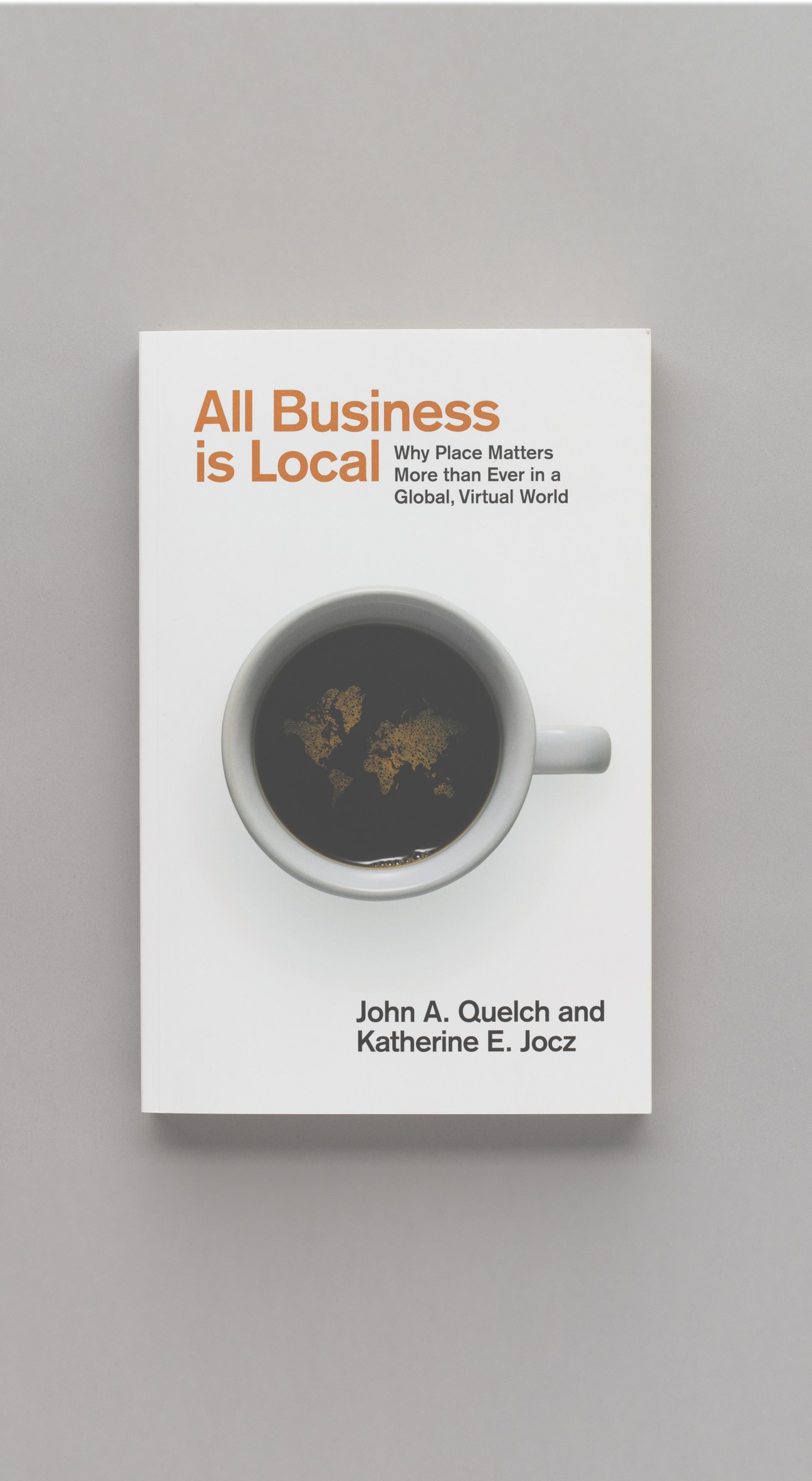 Book cover of "All Business is Local" by John A. Quelch and Katherine E. Jocz featuring a coffee cup with world map design.