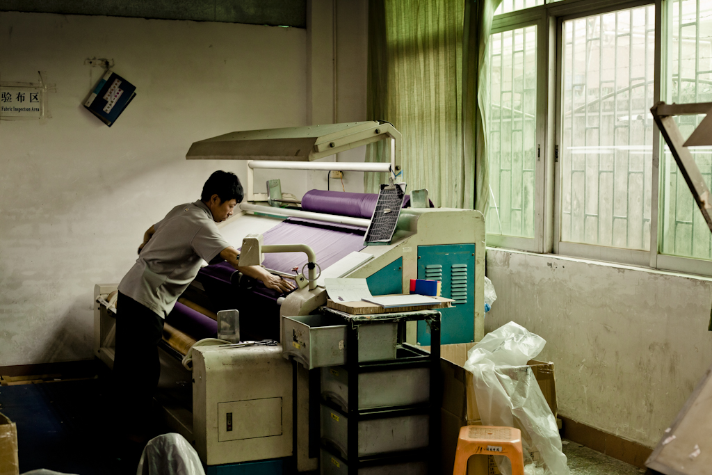 Worker operating industrial textile machinery at Lian Hing factory in Dongguan, which manufactures swimsuits and underwear.