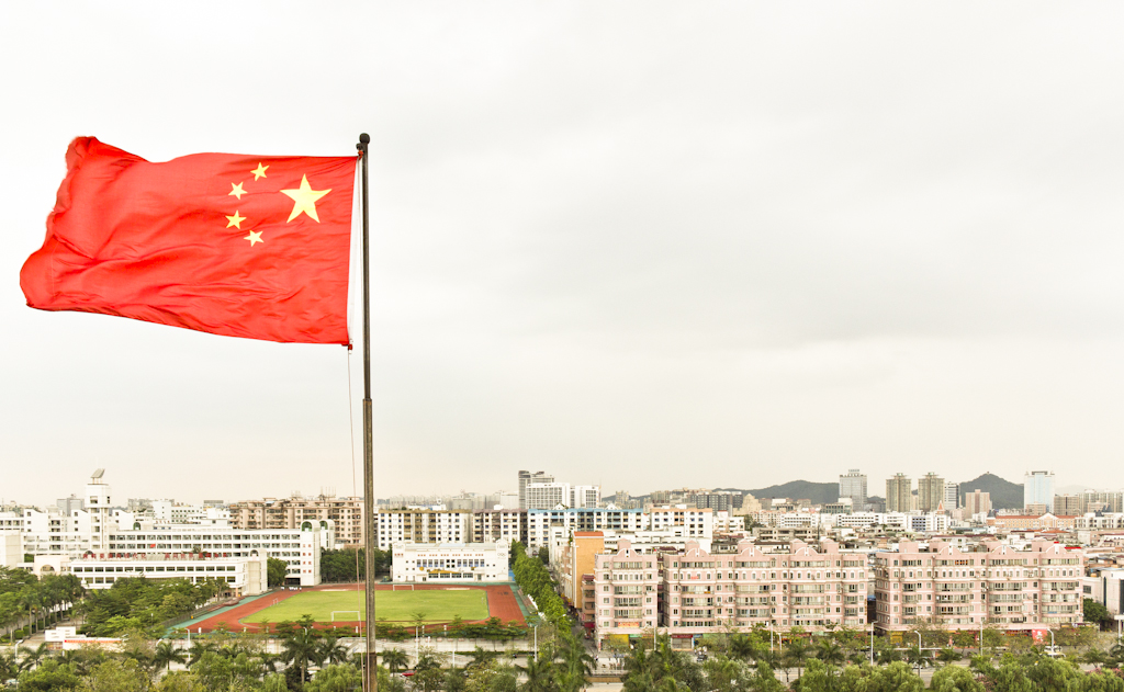 Chinese flag flying above residential apartment buildings and a sports field in Dongguan.