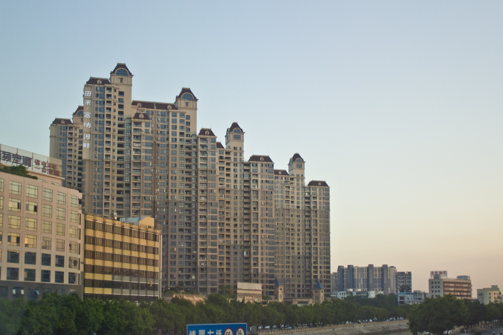 Newly built apartment towers with distinctive peaked roofs line a street in Dongguan.
